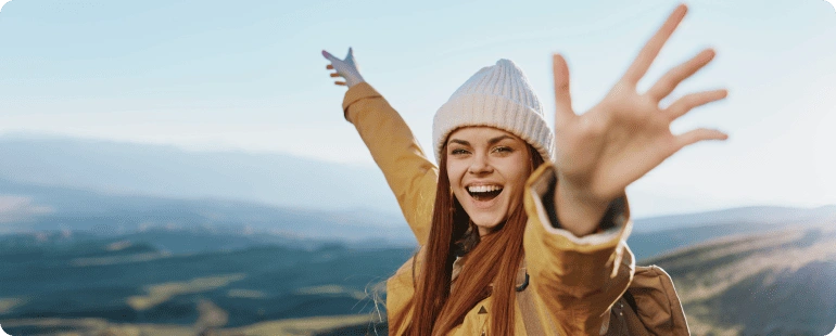 A happy travel nurse embracing adventure in a scenic mountain landscape.
