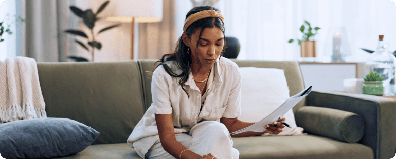 Woman reviewing documents while sitting on a sofa.