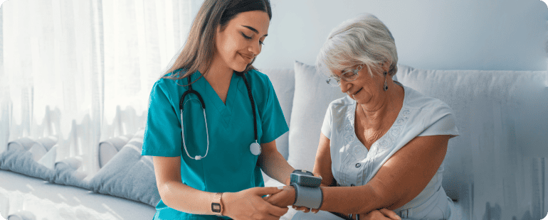 Travel nurse assisting an elderly patient with a blood pressure check.