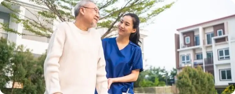 A travel physical therapist helping a senior patient with mobility exercises outside.