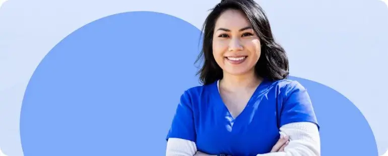 Confident travel nurse wearing blue scrubs smiling outdoors