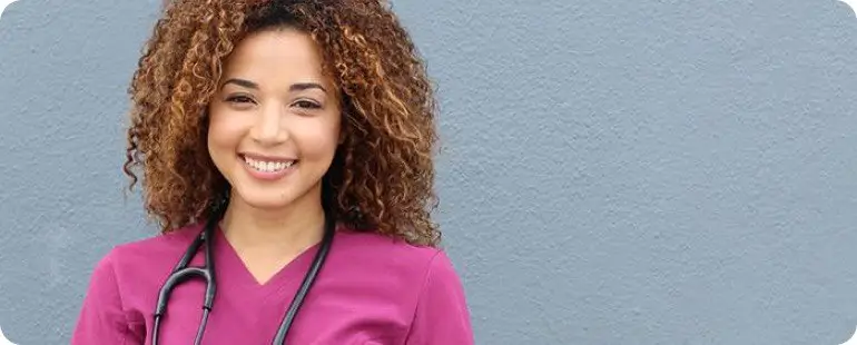 Female nurse in burgundy scrubs smiling with stethoscope around her neck