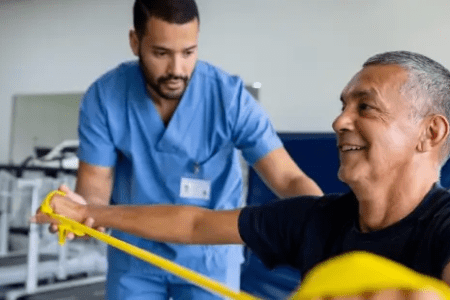 Physical Therapist Assisting Male Patient with Resistance Band Exercise 450x300