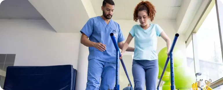 Female patient walking with parallel bars during physical therapy session