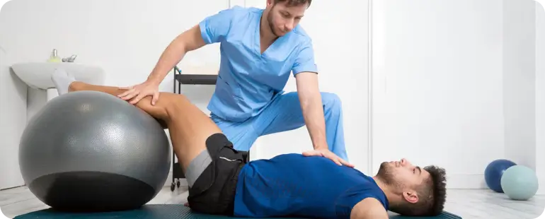Therapist using stability ball for sports physical therapy treatment