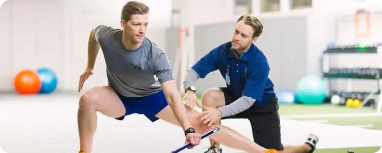 Sports physical therapist guiding athlete through performance rehab drills
