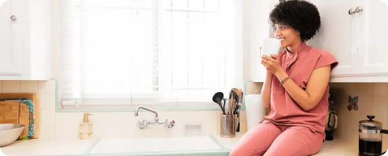Smiling travel nurse enjoying coffee in furnished agency-provided housing kitchen