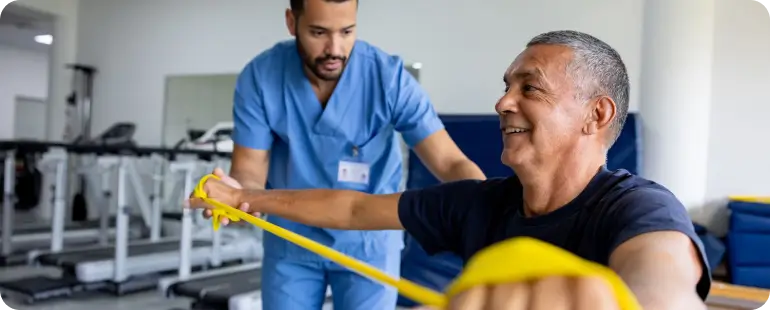 Physical therapist helping male patient with resistance band exercises to improve strength and mobility.